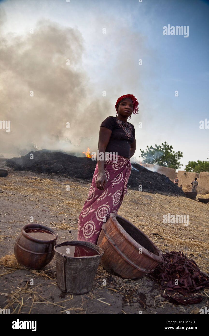 In dem Dorf Kalabougou in Mali, neben der Töpferöfen bereitet eine Frau die Glasur auf die neu gebrannte Keramik. Stockfoto