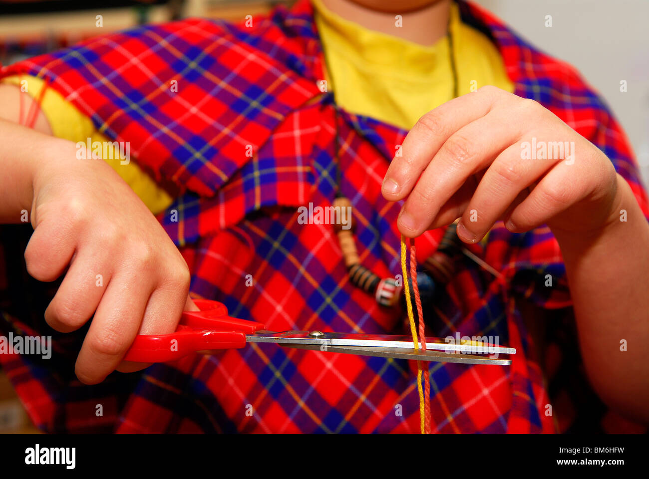 Junge Grundschüler schneiden farbige Wolle mit einer Schere in & Designtechnologie Lektion Grayshott, Haslemere, Großbritannien. Stockfoto