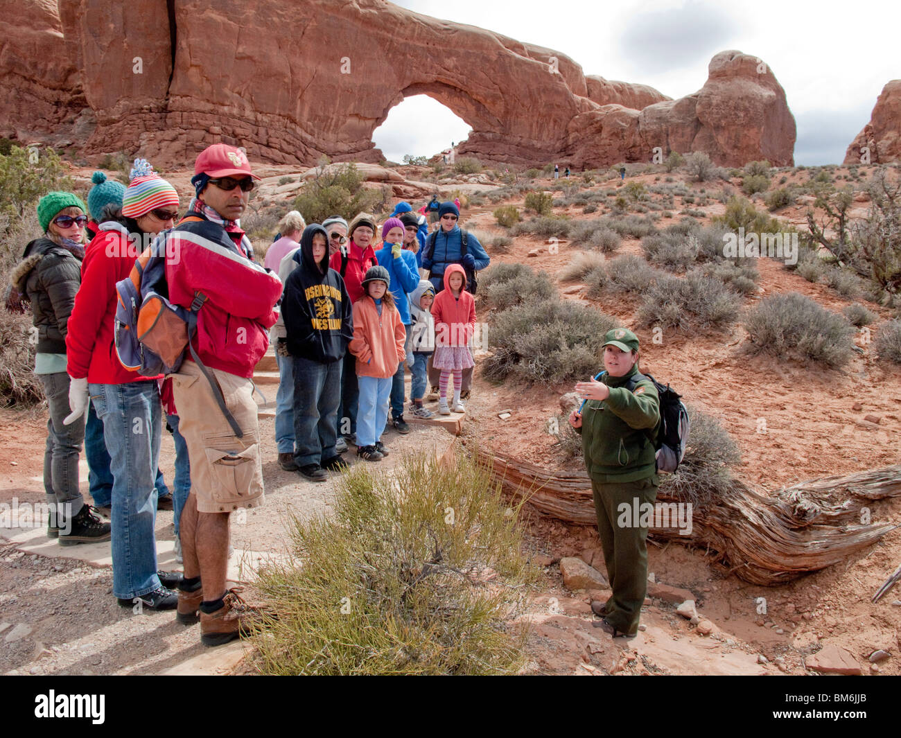 Ein Frau Parkranger spricht für eine Reisegruppe im Arches National Park, Utah. Im Hintergrund ist Schinken Rock. Stockfoto
