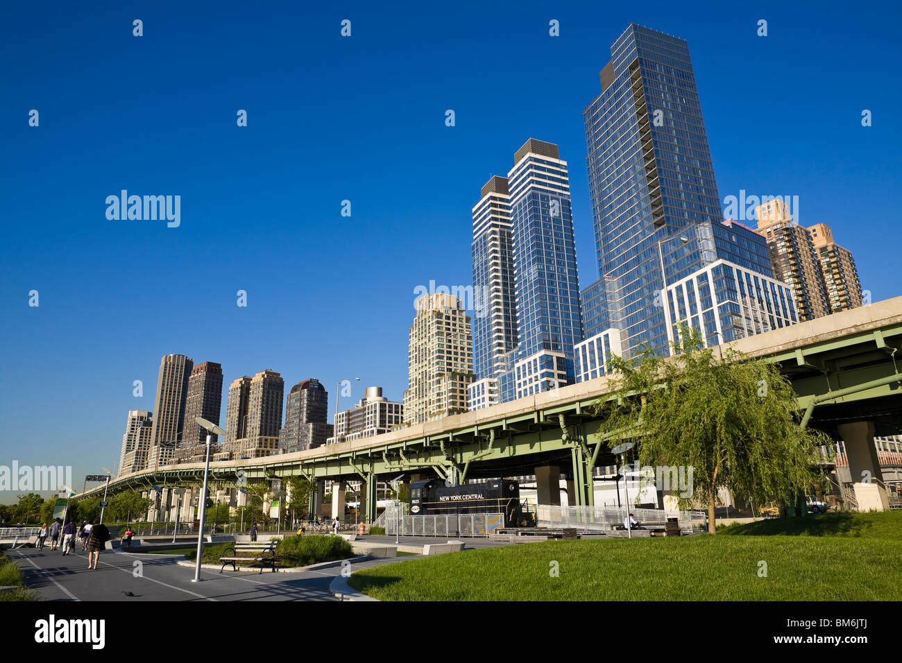 Menschen genießen einen wunderschönen sonnigen Tag zu Fuß durch den Park entlang des Hudson River vor dem Hintergrund der Gebäude. Stockfoto