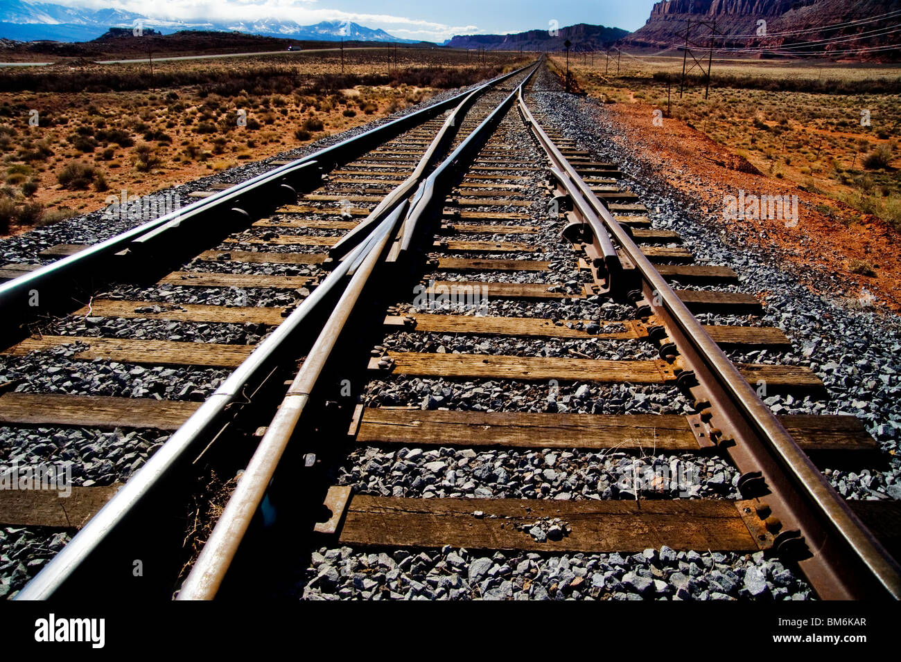 Eisenbahnschienen parallel eine Autobahn in Moab, Utah. Beachten Sie die Berge im Hintergrund. Stockfoto