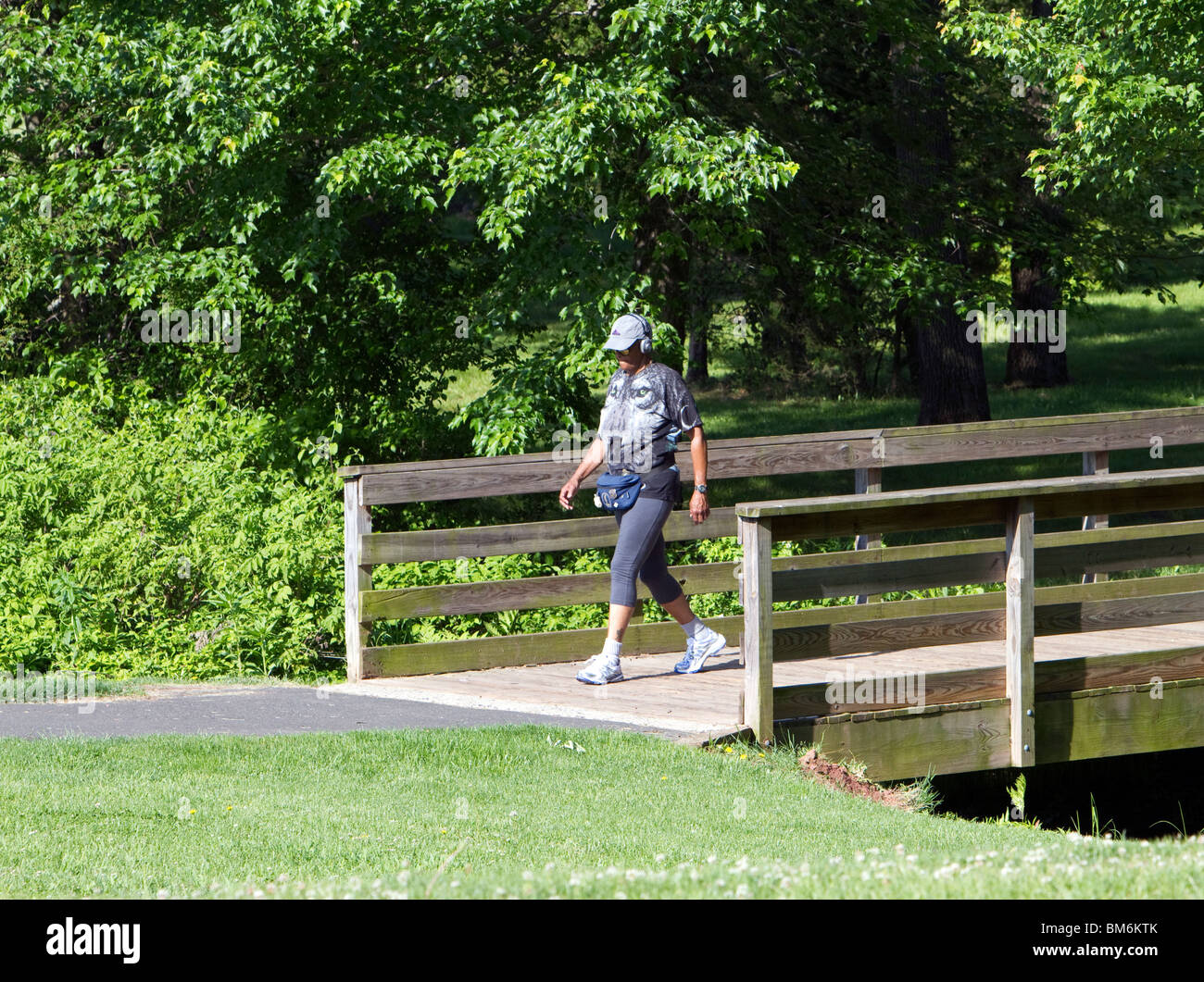 Eine Frau, die zu Fuß über eine Holzbrücke. Stockfoto