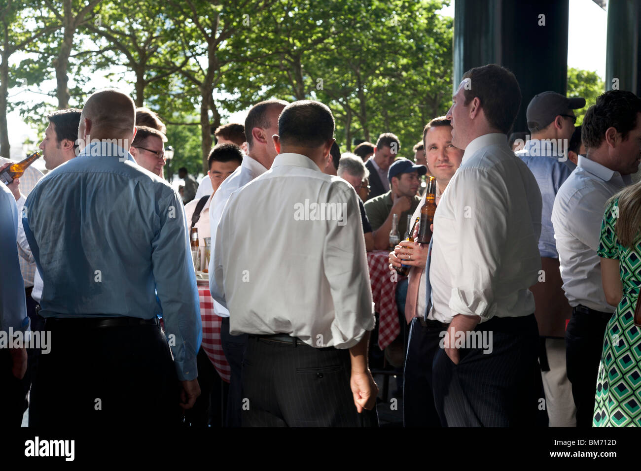 entspannende Geschäftsleute teilen eine gesellige Bier Menge Terrasse des Financial Center Wasserstelle nach der Arbeit am Freitag Stockfoto