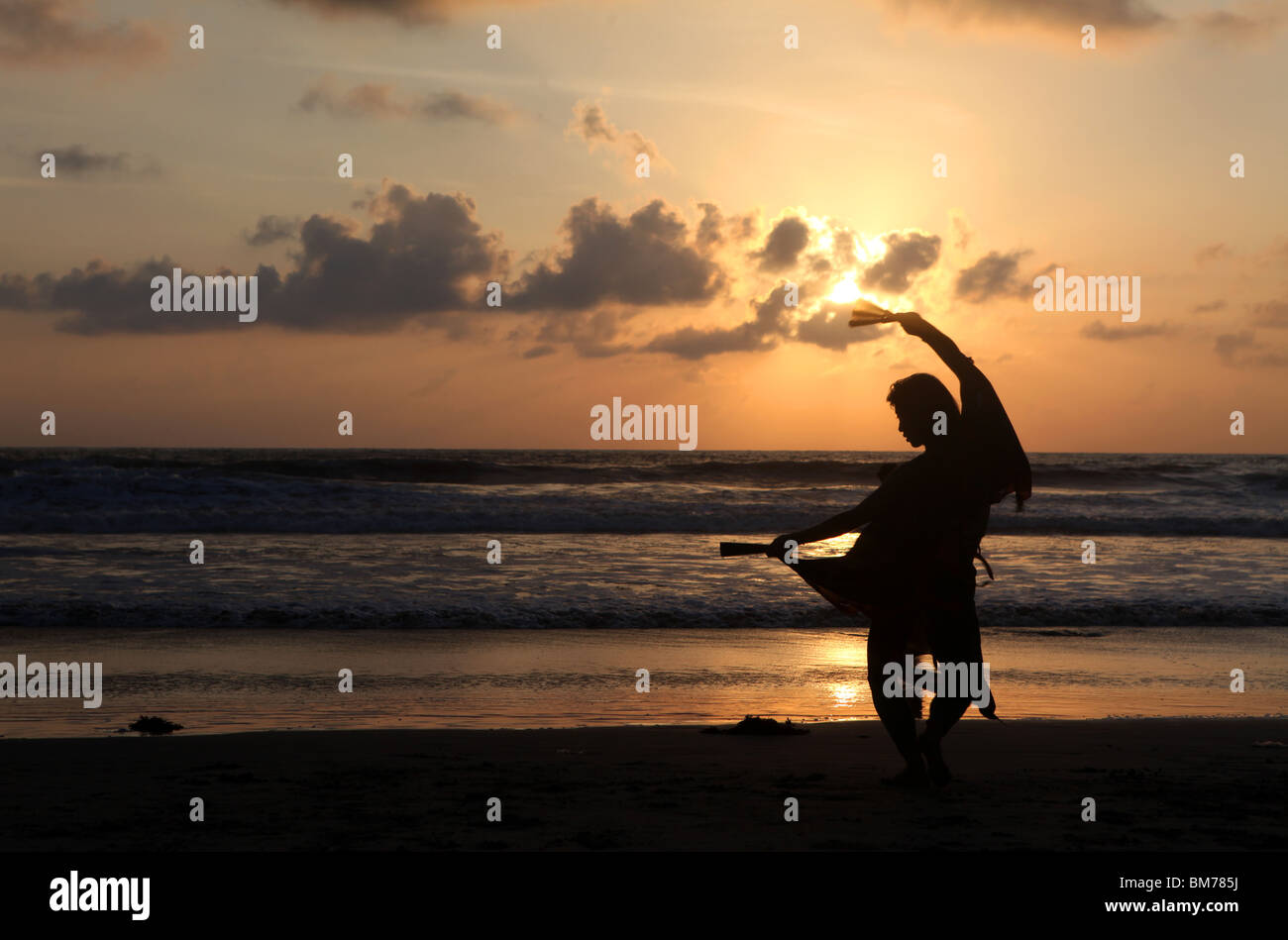 Eine Frau tanzt am Strand von Arambol als die Sonne untergeht in Nord-Goa, Bundesstaat Goa, Indien. Stockfoto
