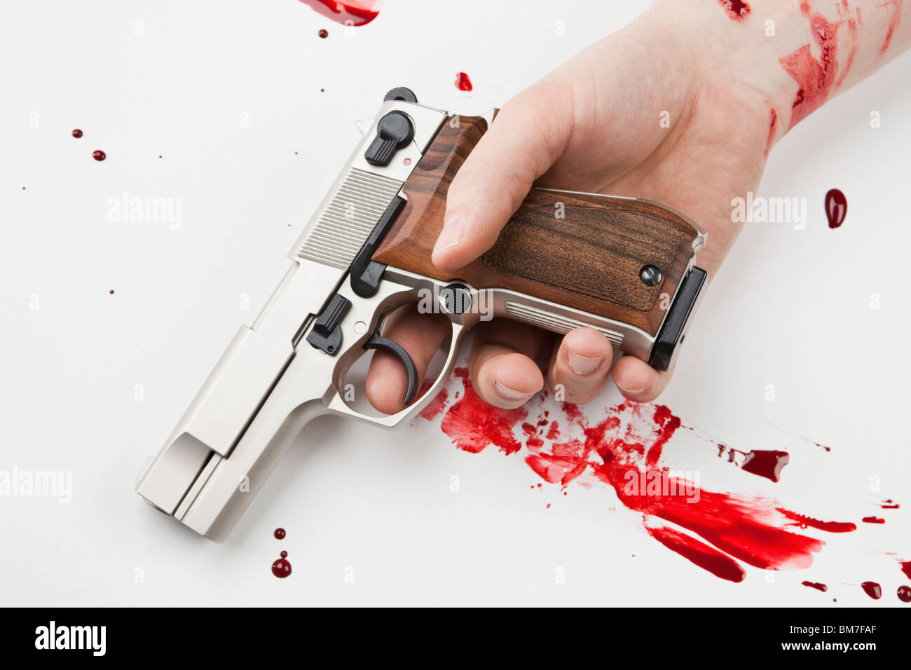 Eine Hand hält eine Pistole mit Blut bespritzt Stockfoto