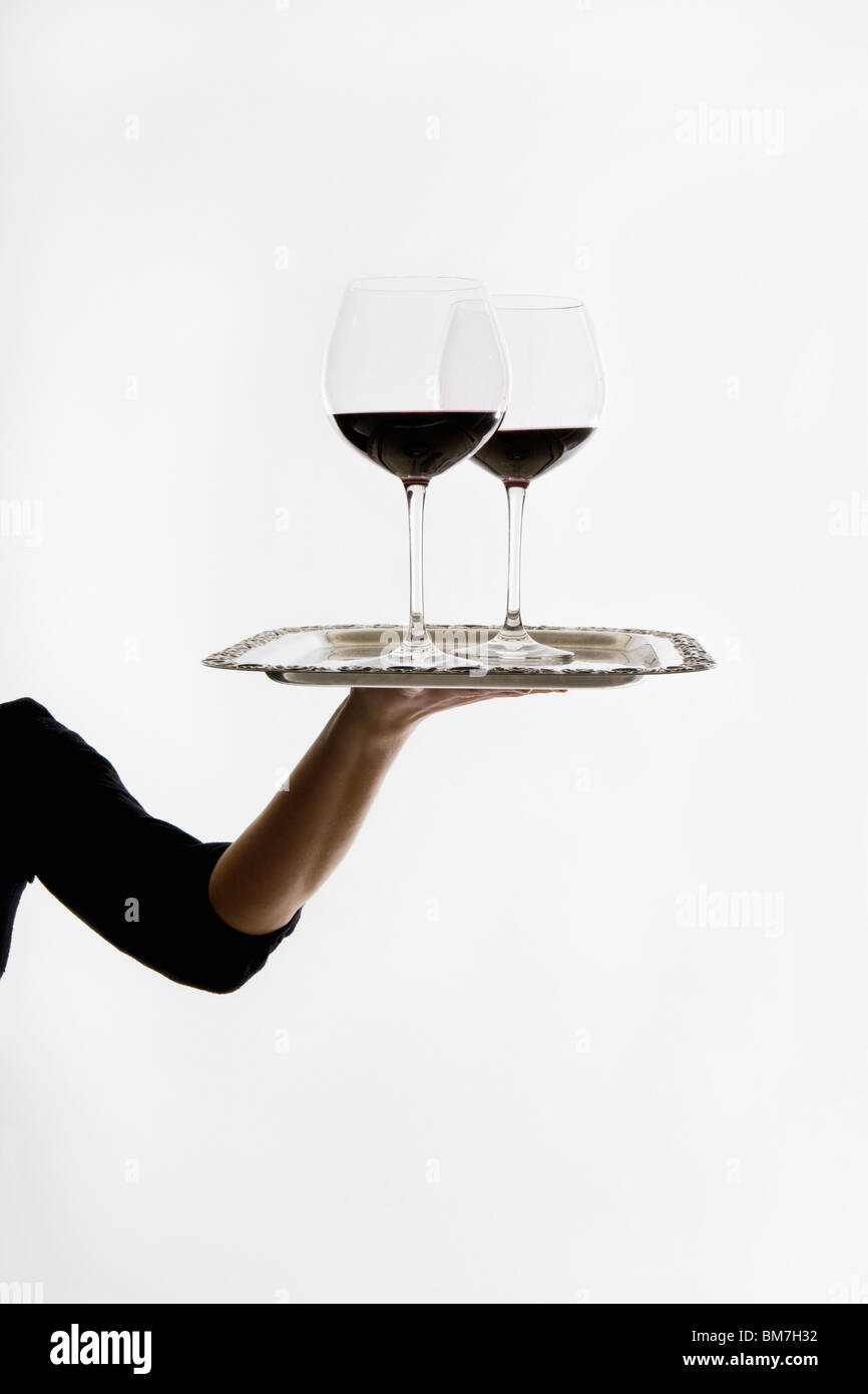 Eine Frau, die zwei Gläser Rotwein auf einem Tablett Stockfoto