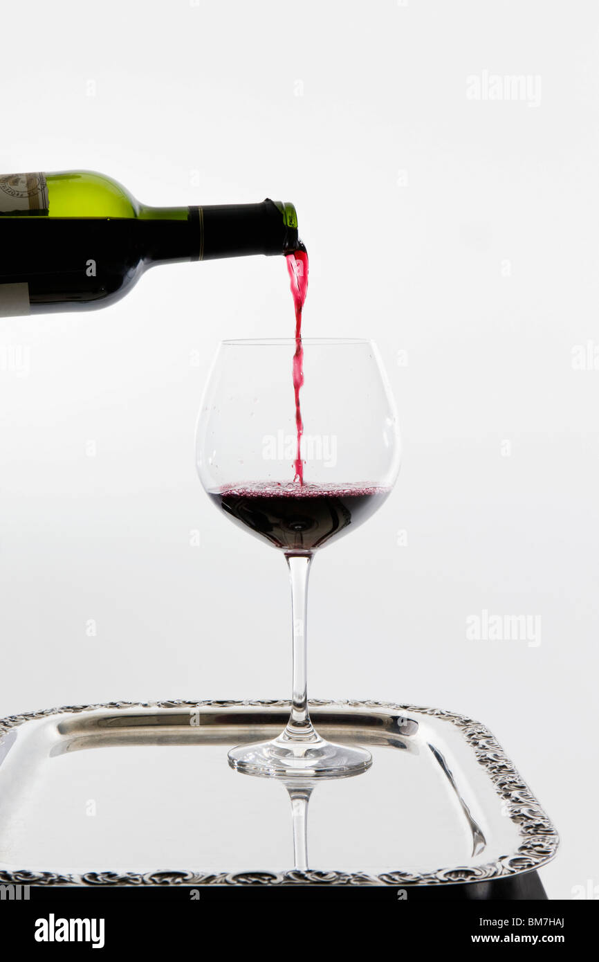 Rotwein wird auf einem Tablett in einem Weinglas gegossen Stockfoto