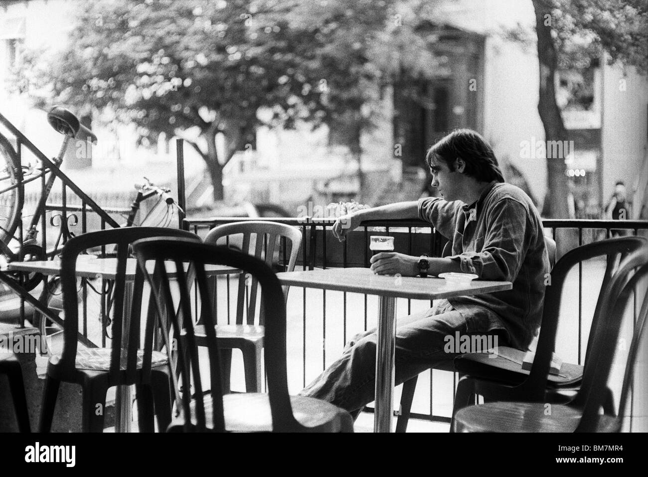 Depressiv wirkende junge Mann sitzt auf Pub Terrasse Blick auf Pint Bier. Stockfoto