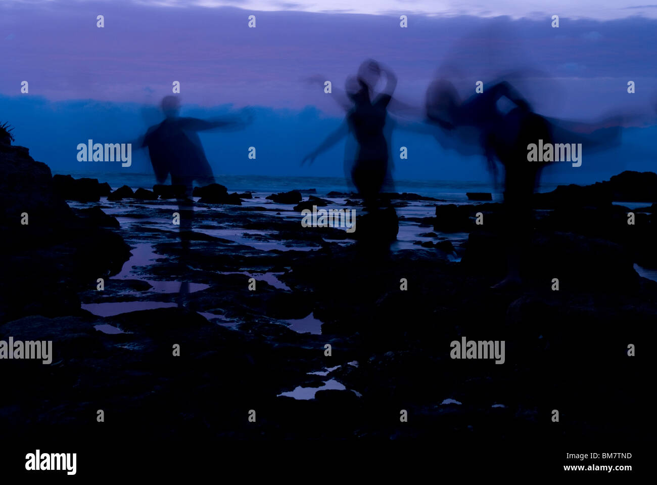 3 Figuren am Meer in der Abenddämmerung Stockfoto
