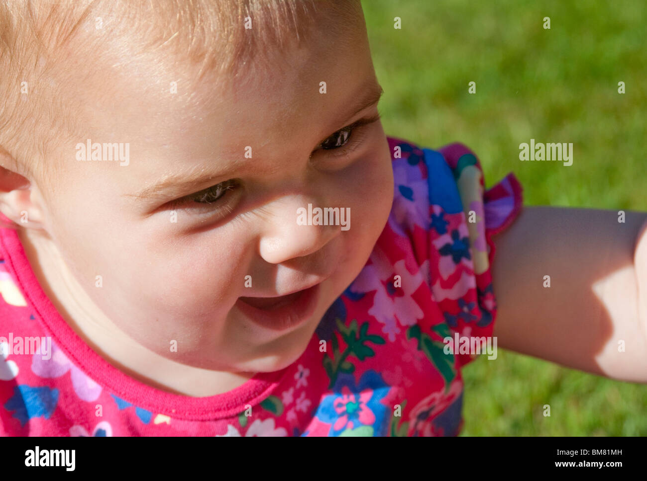 Medium Nahaufnahme Blick hinunter auf 1 Jahr alte weibliche Kleinkind lächelnd aus Frame hellen Farben hellen Tageslicht Stockfoto