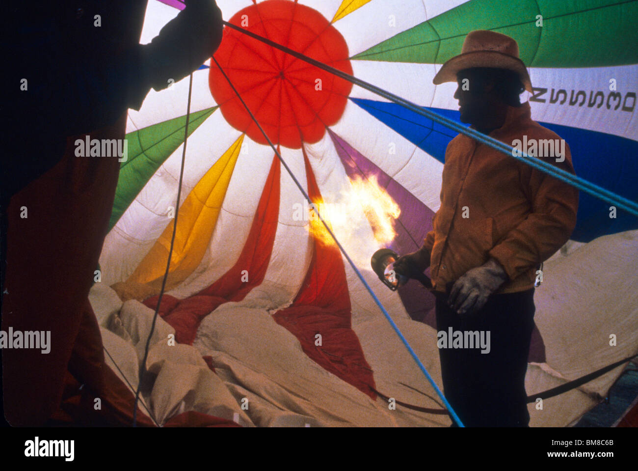 Mann halten große Propan Brenner beginnen aufblasen Heißluftballon Feuer Flamme Physik Spaß Erholung fliegen Aufzug Himmelsfarbe Stockfoto