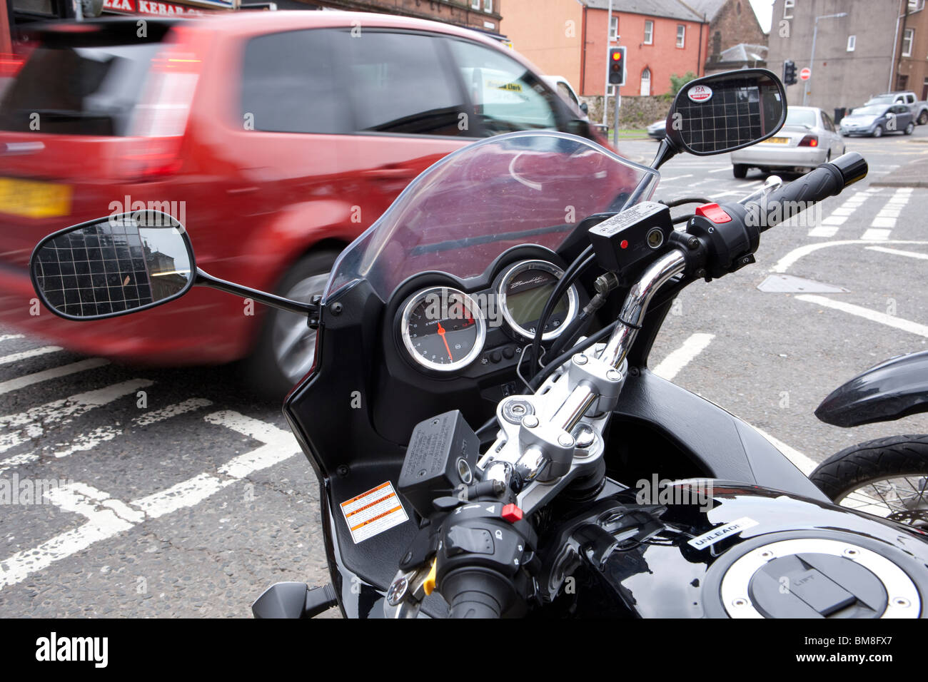 Im Motorrad-Stadt wählt Lenker blickte auf Tacho und Instrumente mit Auto beschleunigt vorbei im Hintergrund Stockfoto
