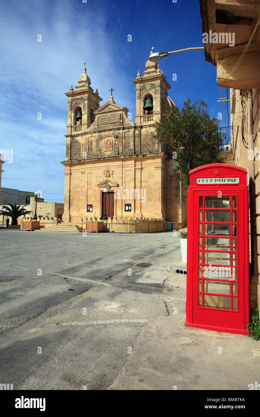 Eine rote britische Telefonzelle sitzt alleine in ein leeres Quadrat in einem mediterranen Ambiente in einem Dorf auf der Insel Gozo, Malta Stockfoto