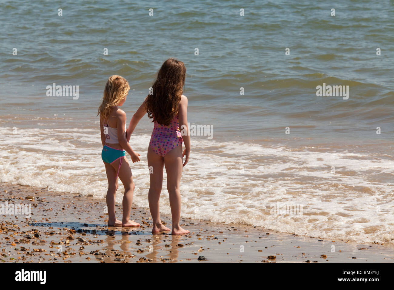 zwei junge Mädchen im Bad passt zusammen stehen am Rand des Meeres am Strand mit Blick auf das Meer Stockfoto