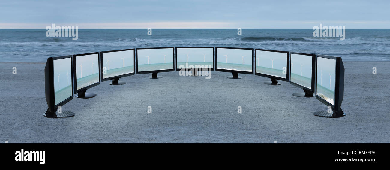 Flachbild-Fernseher mit Bildern von Windkraftanlagen aufgereiht am Strand Stockfoto