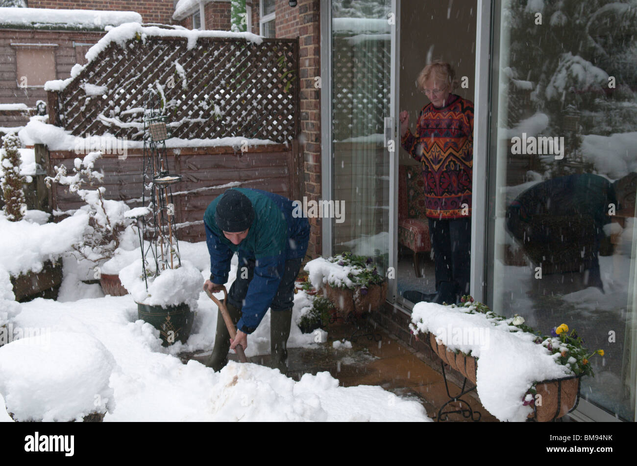 Nachbar relative helfen älteren Menschen durch Schneeräumung von Pfad Stockfoto