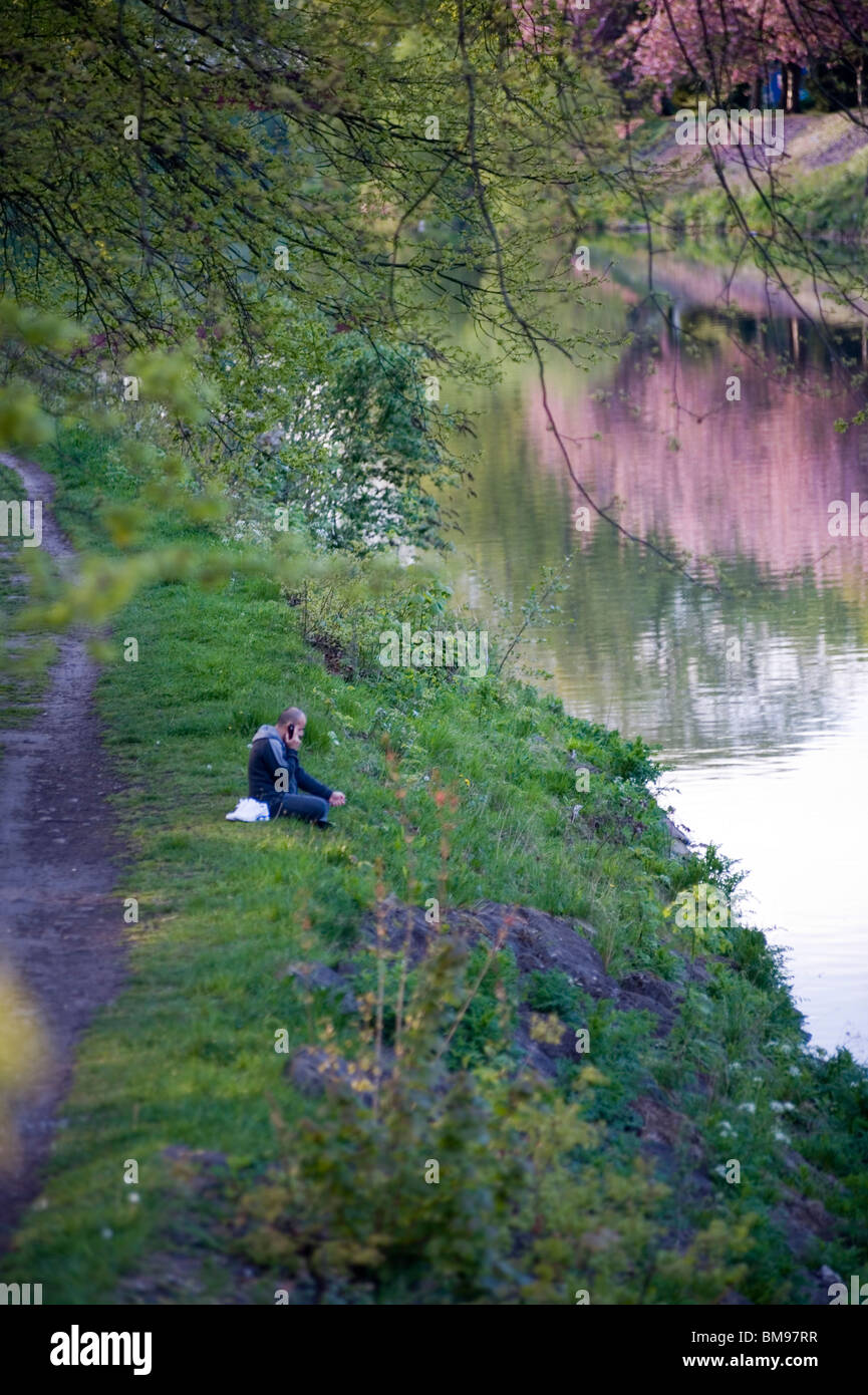 Telefonieren mit Handy Mann saß am Ufer des Flusses Fluss Taff Cardiff Wales UK Großbritannien Stockfoto