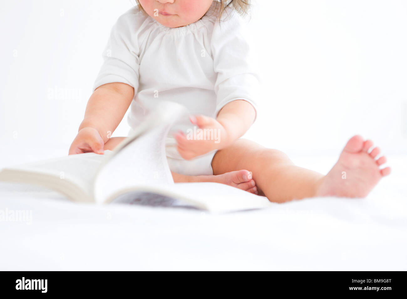 Baby Mädchen drehen Seite des Buches Stockfoto