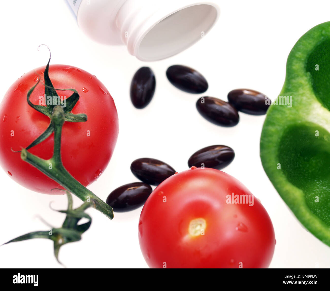 Vitamin Pillen mit Tomaten und Paprika. Pillen oder frisches Gemüse für Ernährung. Vergleich vitamin Pillen v frische Lebensmittel. Stockfoto