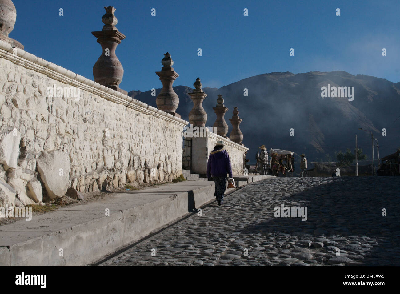 Frau zu Fuß neben Kirchenmauer nahe Colca Canyon, Peru Stockfoto
