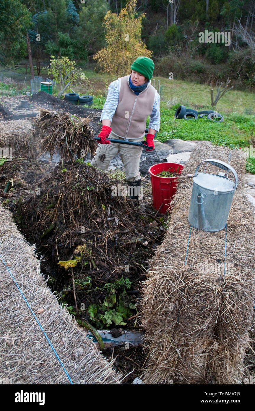 Frau drehen einen Komposthaufen Wurm Bauernhof inmitten von Heuballen Stockfoto