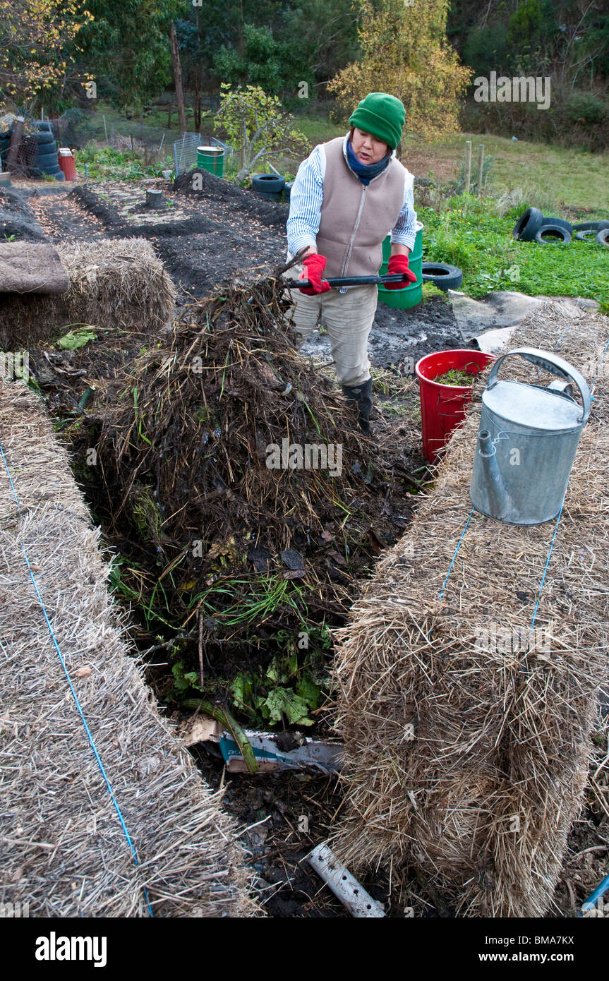 Frau drehen einen Komposthaufen Wurm Bauernhof inmitten von Heuballen Stockfoto