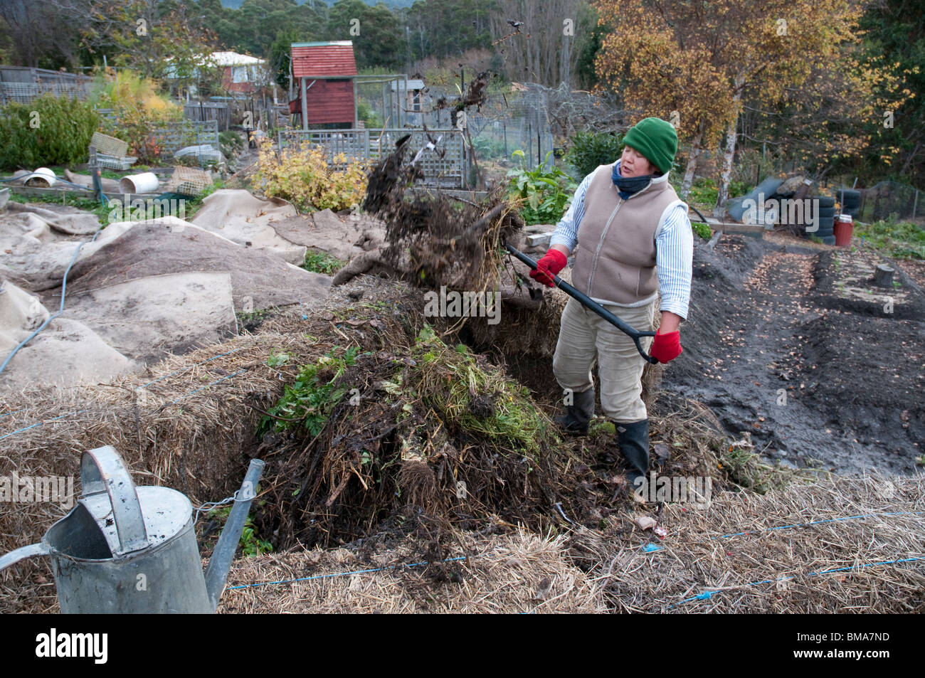 Frau drehen einen Komposthaufen Wurm Bauernhof inmitten von Heuballen Stockfoto