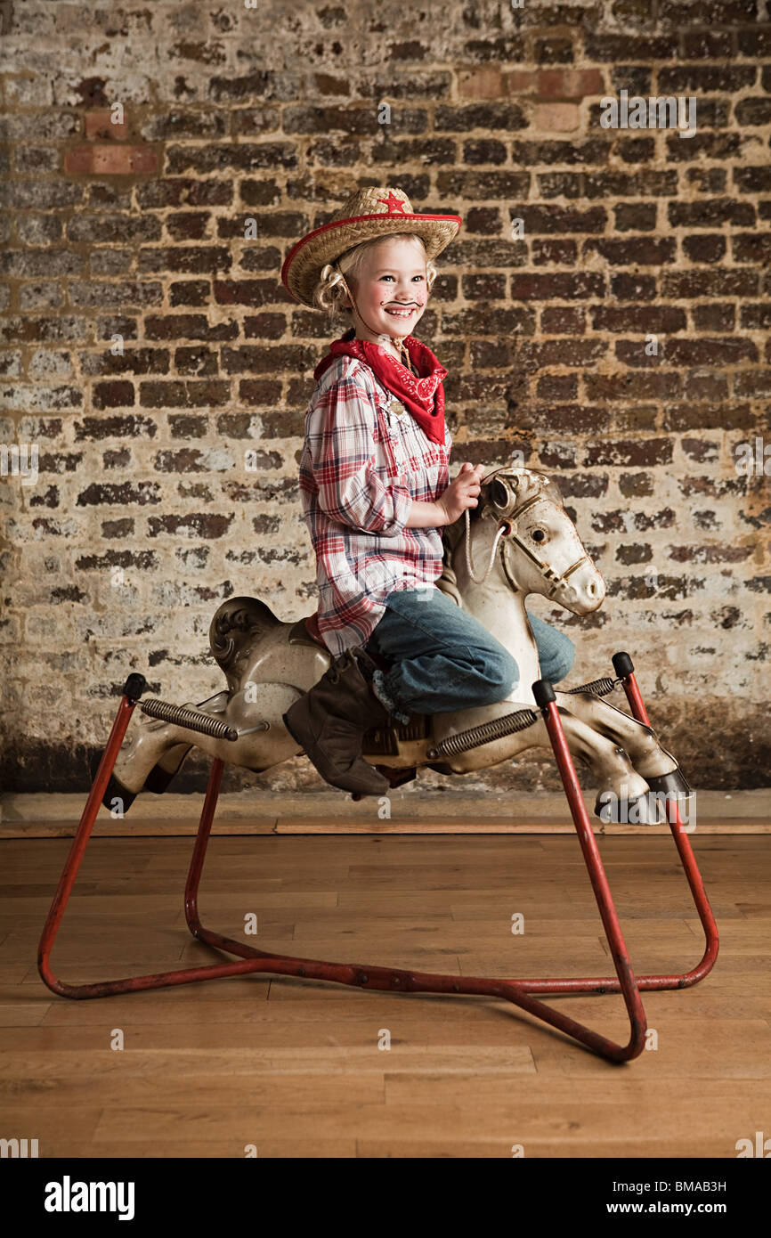 Junges Mädchen gekleidet als Cowgirl mit Schaukelpferd Stockfoto