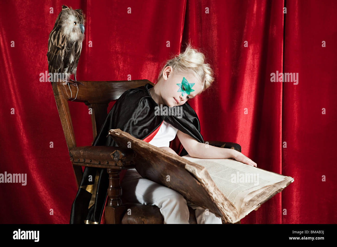 Junges Mädchen verkleidet als Zauberer schlafend mit Zauberbuch Stockfoto