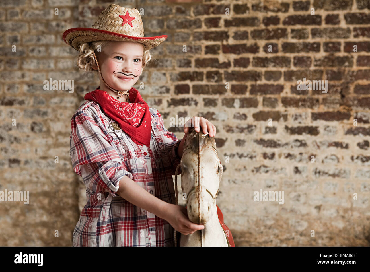 Junges Mädchen gekleidet als Cowgirl mit Schaukelpferd Stockfoto