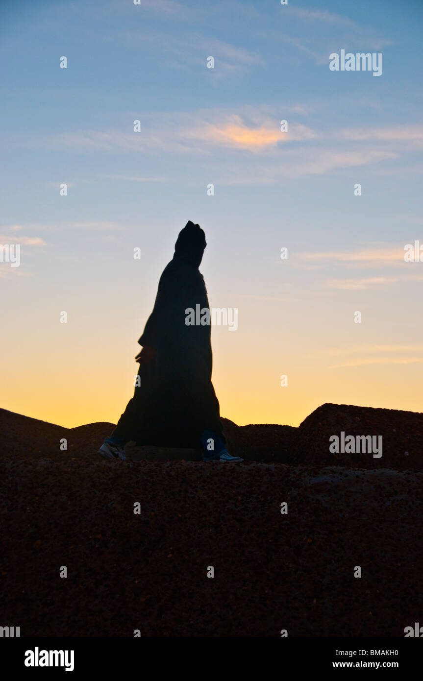 Marokko Asilah getarnte Jellabah Mann ging bei Sonnenuntergang Stockfoto