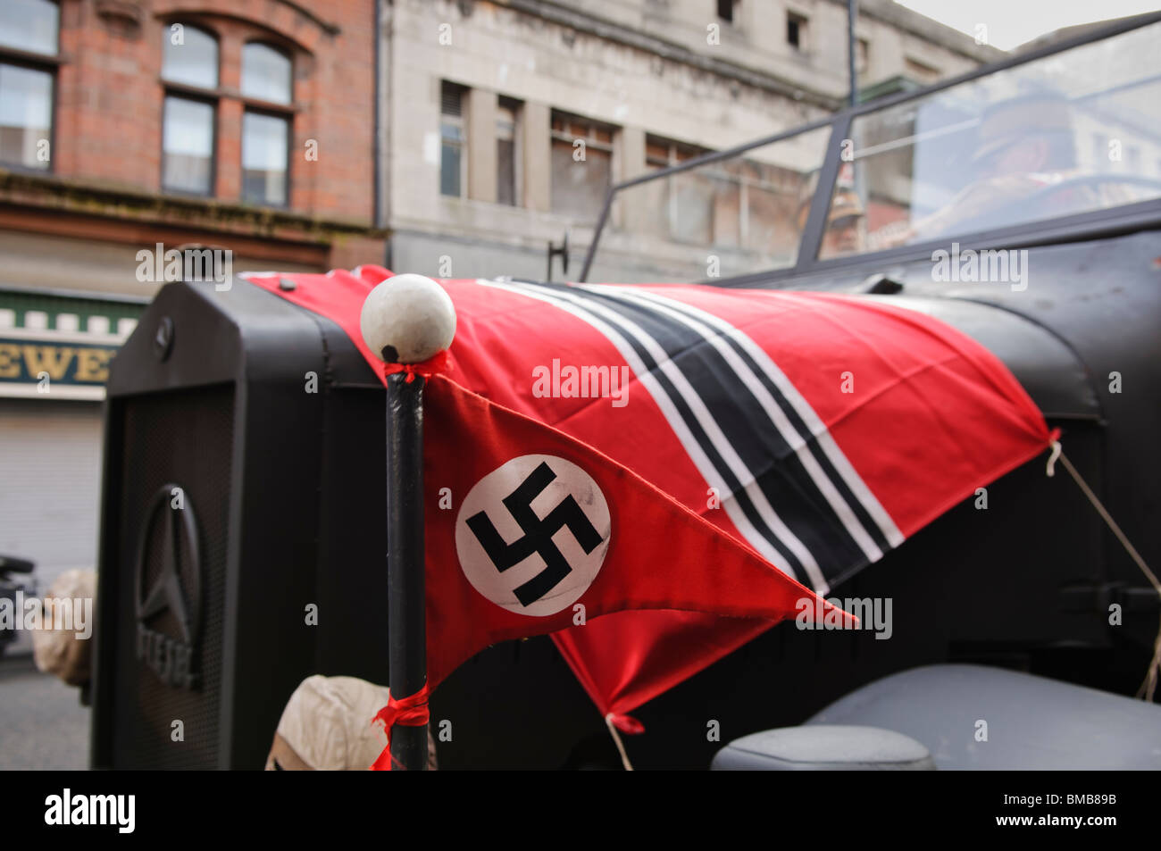 Nazi-Flaggen auf der Motorhaube eines Bundeswehr-LKW bei den Dreharbeiten eines Films in Berlin der 1930er Jahre gesetzt. Stockfoto
