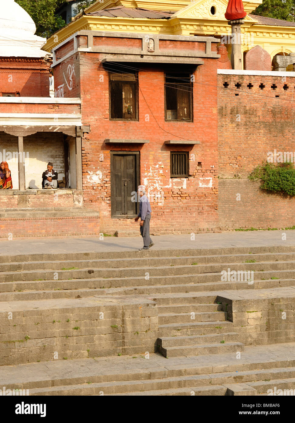 nepalesische Greis zu Fuß entlang der Aussichtspunkt mit Blick auf die Feuerbestattung Ghats am Pashupatinath Hindu Tempel, Kathmandu, nepal Stockfoto