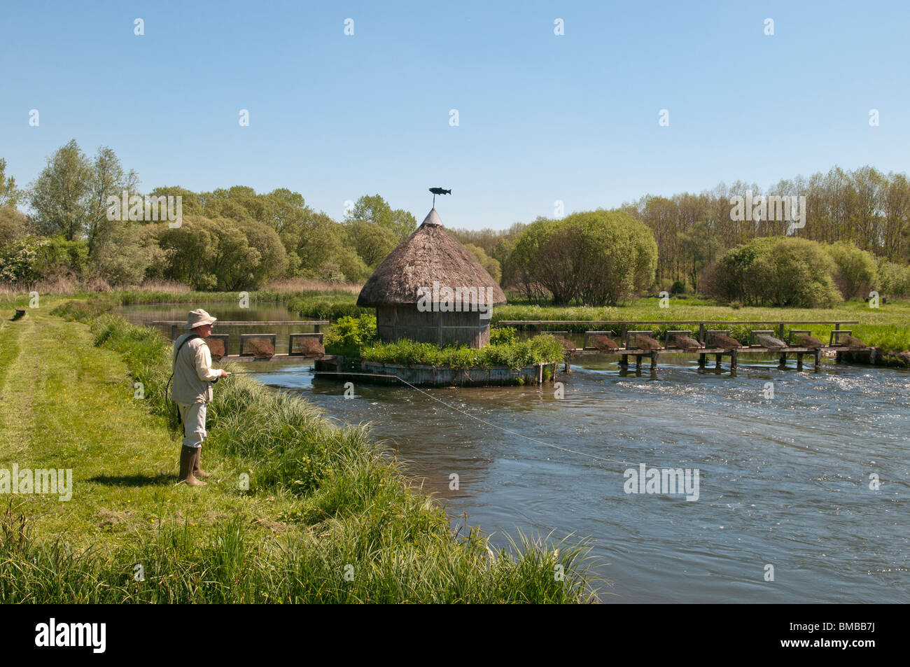 Fliegenfischen Sie auf dem Fluss-Test in Longstock, Hampshire, England. Reusen und einer Gillies schilfgedeckten Hütte zu sehen. Stockfoto