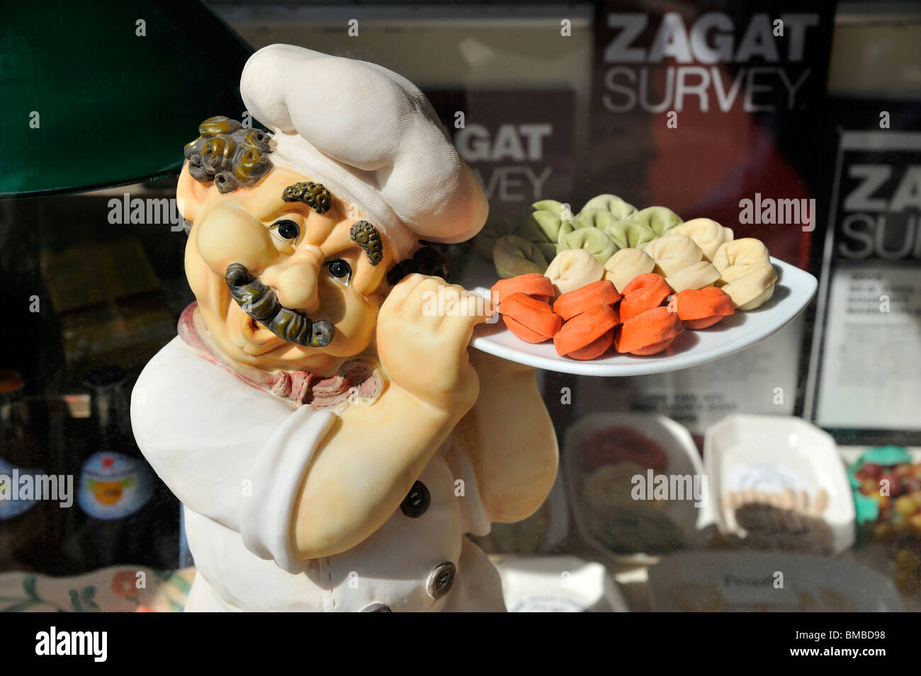 Cartoon-Modell Statue hält eine Schüssel mit Tortellini in den Farben der italienischen Flagge. Stockfoto