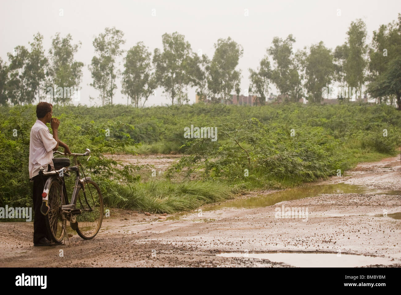 Mann steht auf schlammigen Straße mit dem Fahrrad, Delhi, Indien Stockfoto