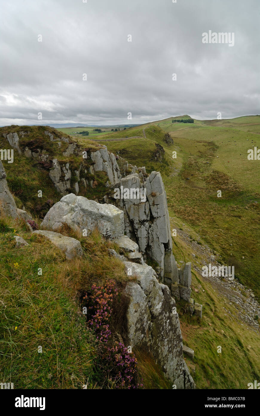 Eine Wand aus Fels in der Nähe von Walltown Klippen, Northumberland. Der Hadrianswall verläuft von oben auf den Hügeln in der Ferne. Stockfoto