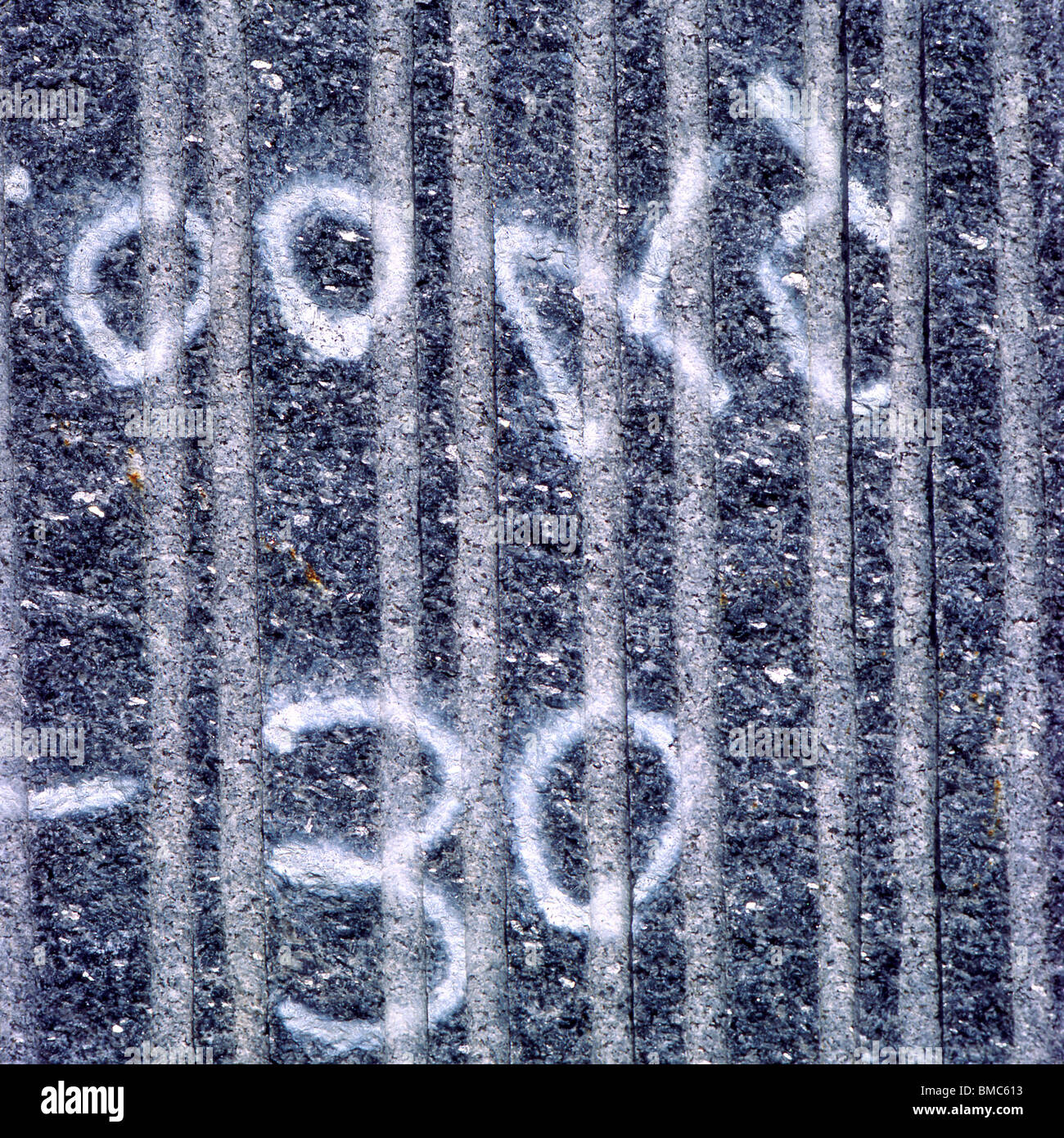 Oberflächenmarkierungen auf einer strukturierten grauen Wand zeigen numerische Symbole, die Messungen oder Referenzen anzeigen Stockfoto