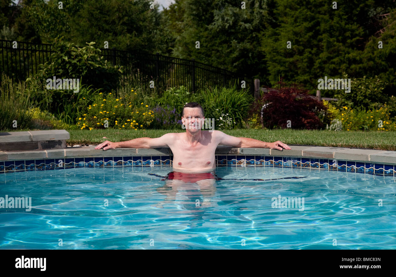 Mann in den Fünfzigern entspannend in einem Pool in einem Hinterhofgarten Stockfoto