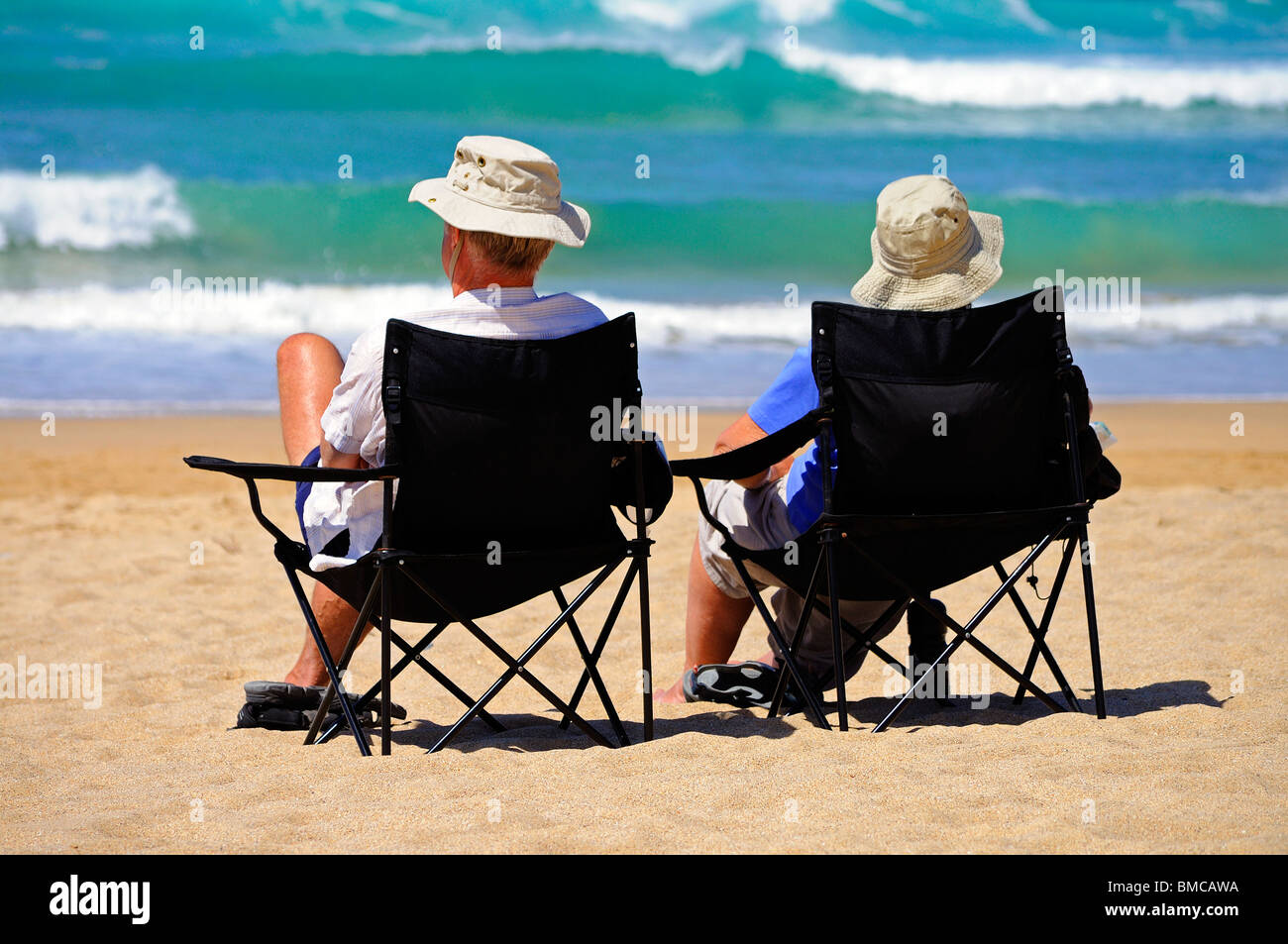 ein Mann und eine Frau sitzen an der Küste an einem Strand in Cornwall, Großbritannien Stockfoto