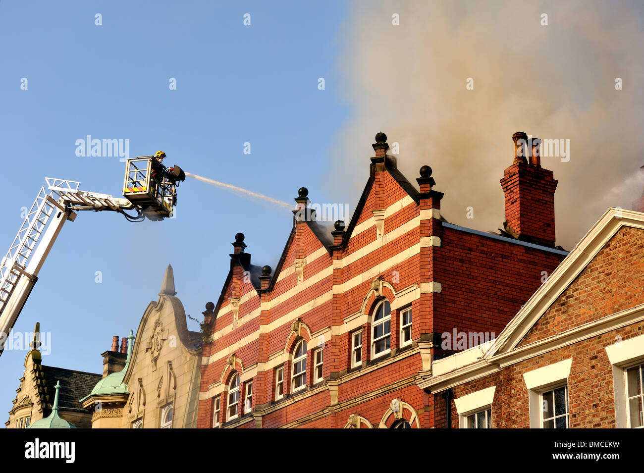 Feuerwehr-Hebebühne sprüht Wasser in Dach-Brand Stockfoto