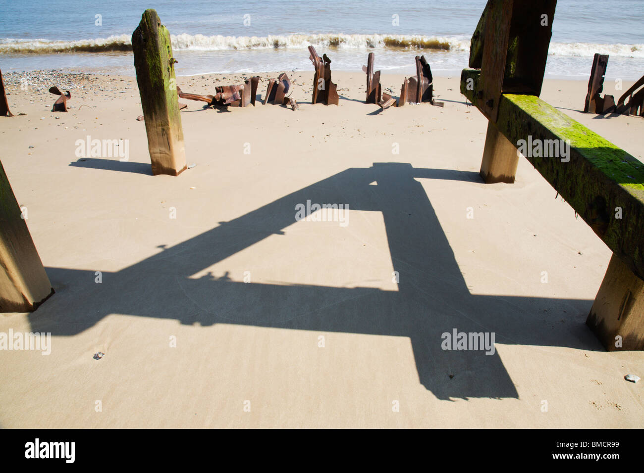 Schatten der Holzpfosten eine Reihe 4 auf Happisburgh Strand machen. Stockfoto