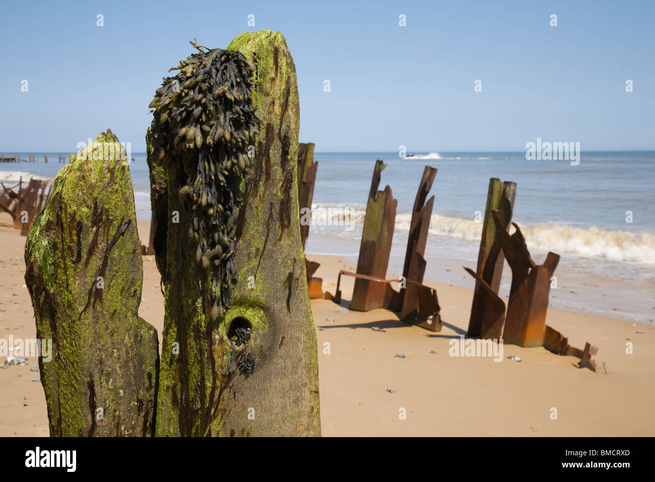 Hölzernen Pfosten und verdreht rostigen Metall entlang Happisburgh Küste, Norfolk. Stockfoto