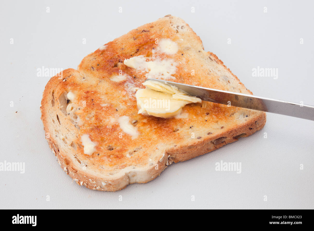 Butter Schmelzen auf eine Scheibe warmen Braun Toast mit einem Messer zu verbreiten Stockfoto