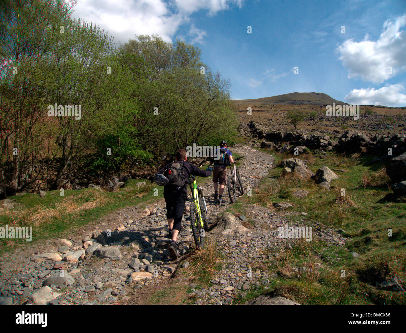Zwei Radfahrer drängen Mountainbikes herauf die steilen und rauhen Walna Narbe-Straße Richtung Westen, in der Nähe von breiten Haws, Cumbria Stockfoto