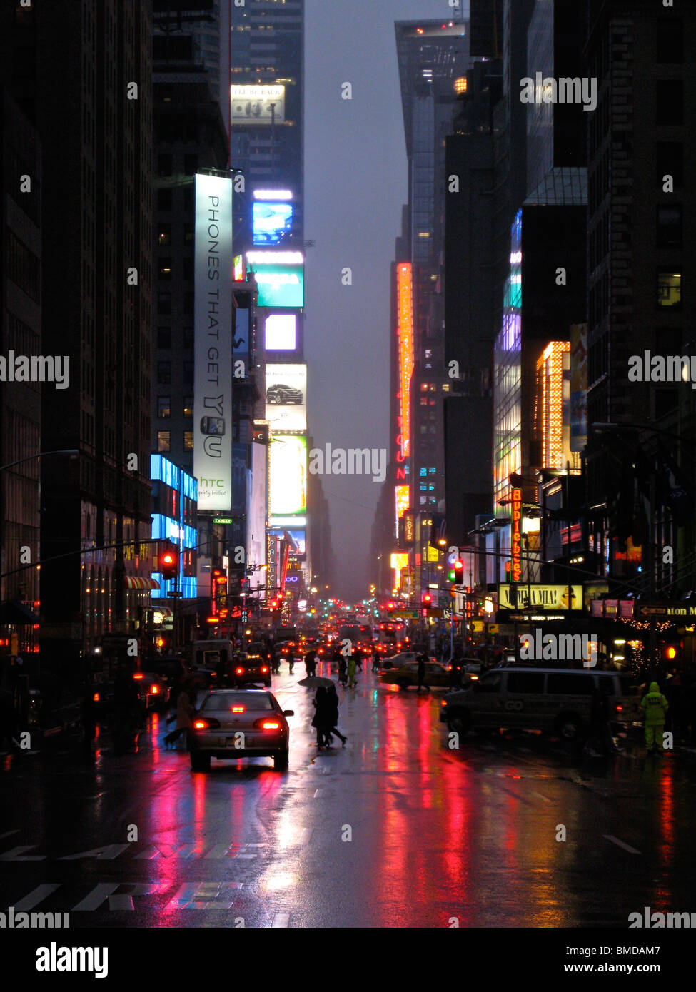 Times Square New York, in der Nacht aus der Ferne gesehen. Die bunten Neon reflektiert auf der nassen Straße. Stockfoto