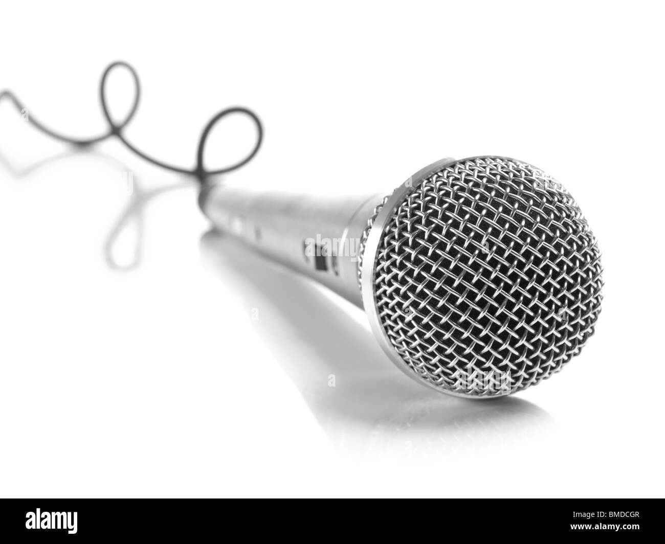 Ein dynamisches Mikrofon mit einem gekräuselten Kabel über weiß. Stockfoto