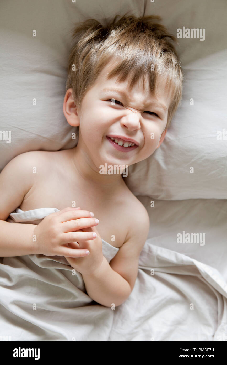 Kleiner Junge im Bett lachen Stockfoto