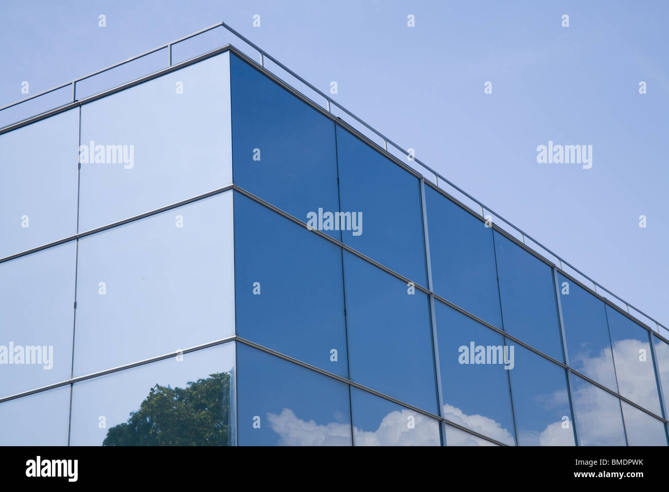 Moderner Glasbau mit Bäumen und Wolken reflektiert es. Stockfoto
