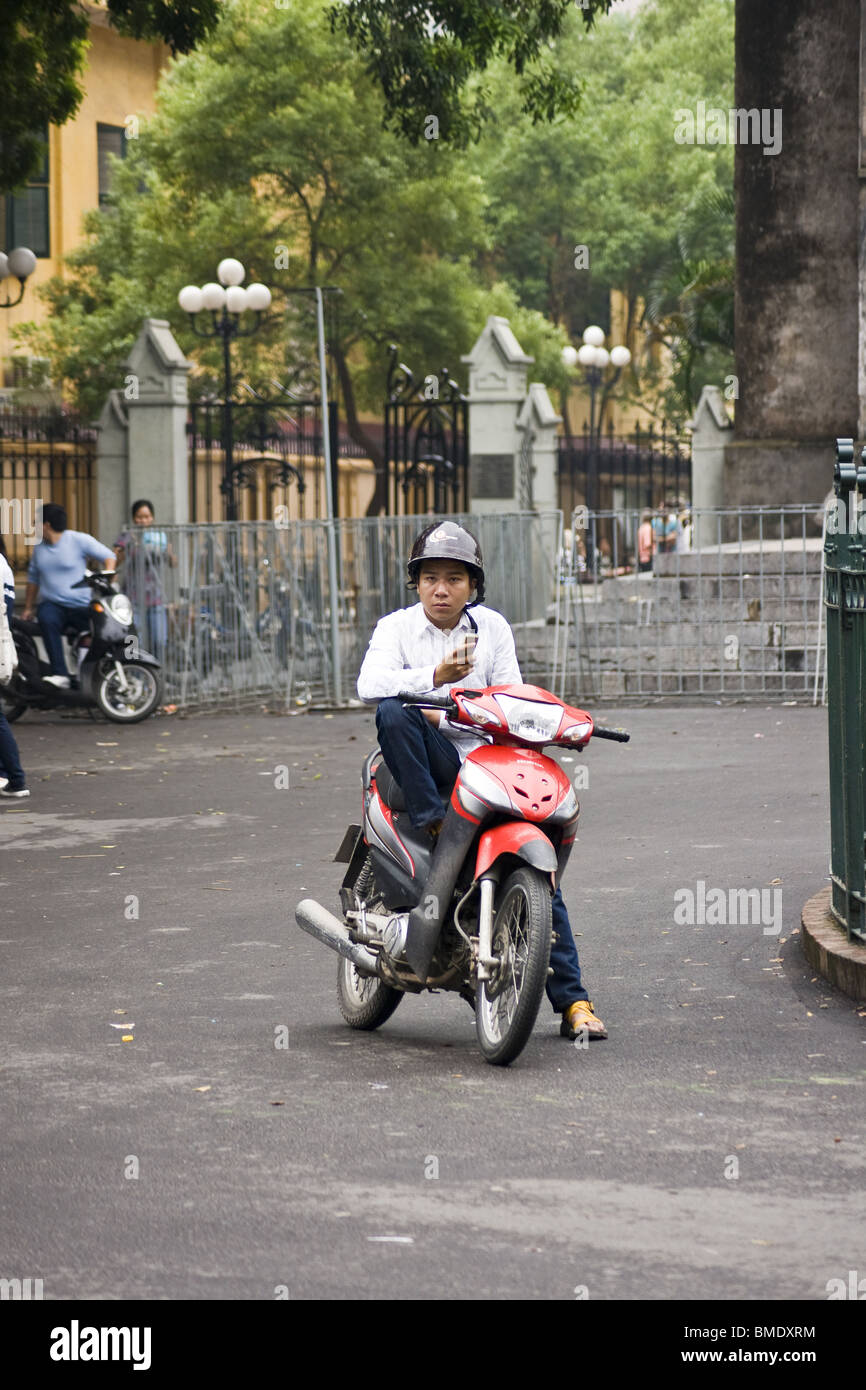 Mann überprüfen Handy auf Motorrad, Vietnam Stockfoto